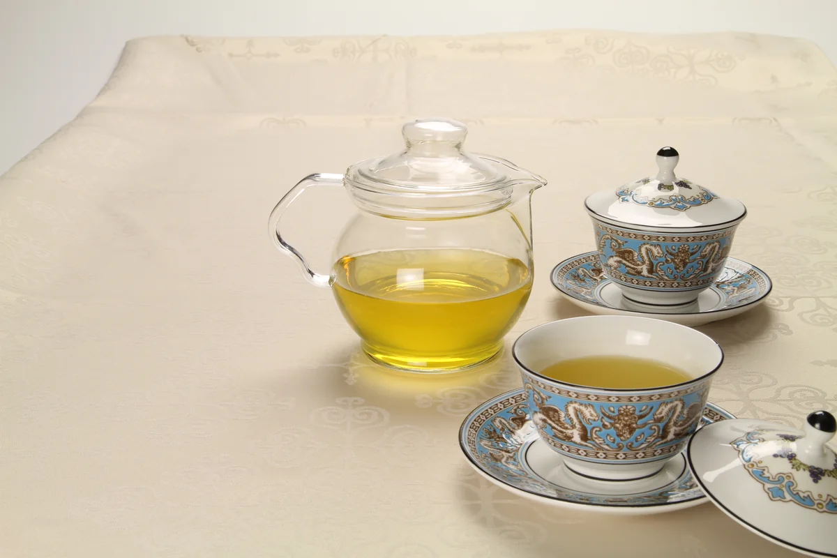 ウェッジウッド フロレンティーン ターコイズ 蓋付き茶杯ペアと、透明なガラスポットの緑茶 ─ 中国意匠のターコイズボーダー、静かなテーブル